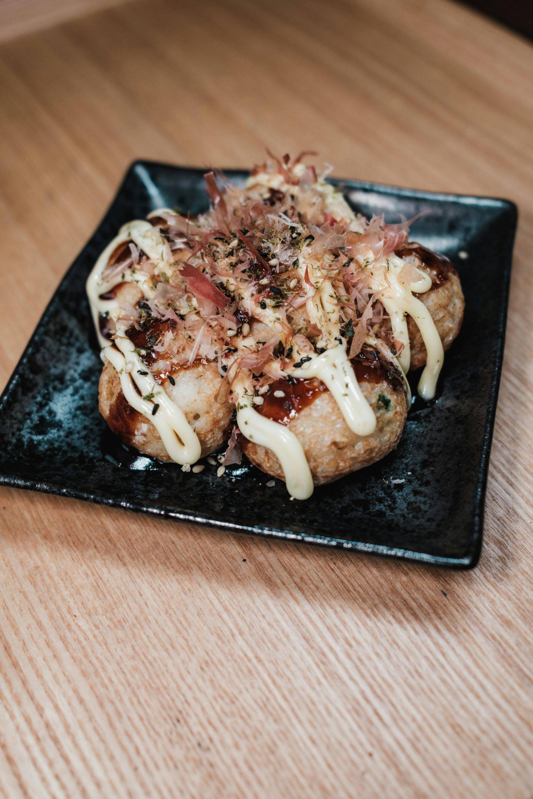 Assiette de Takoyaki soupoudré de feuilles de thon séchées au-dessus avec de la sauce mayonnaise japonaise et sauce rouge